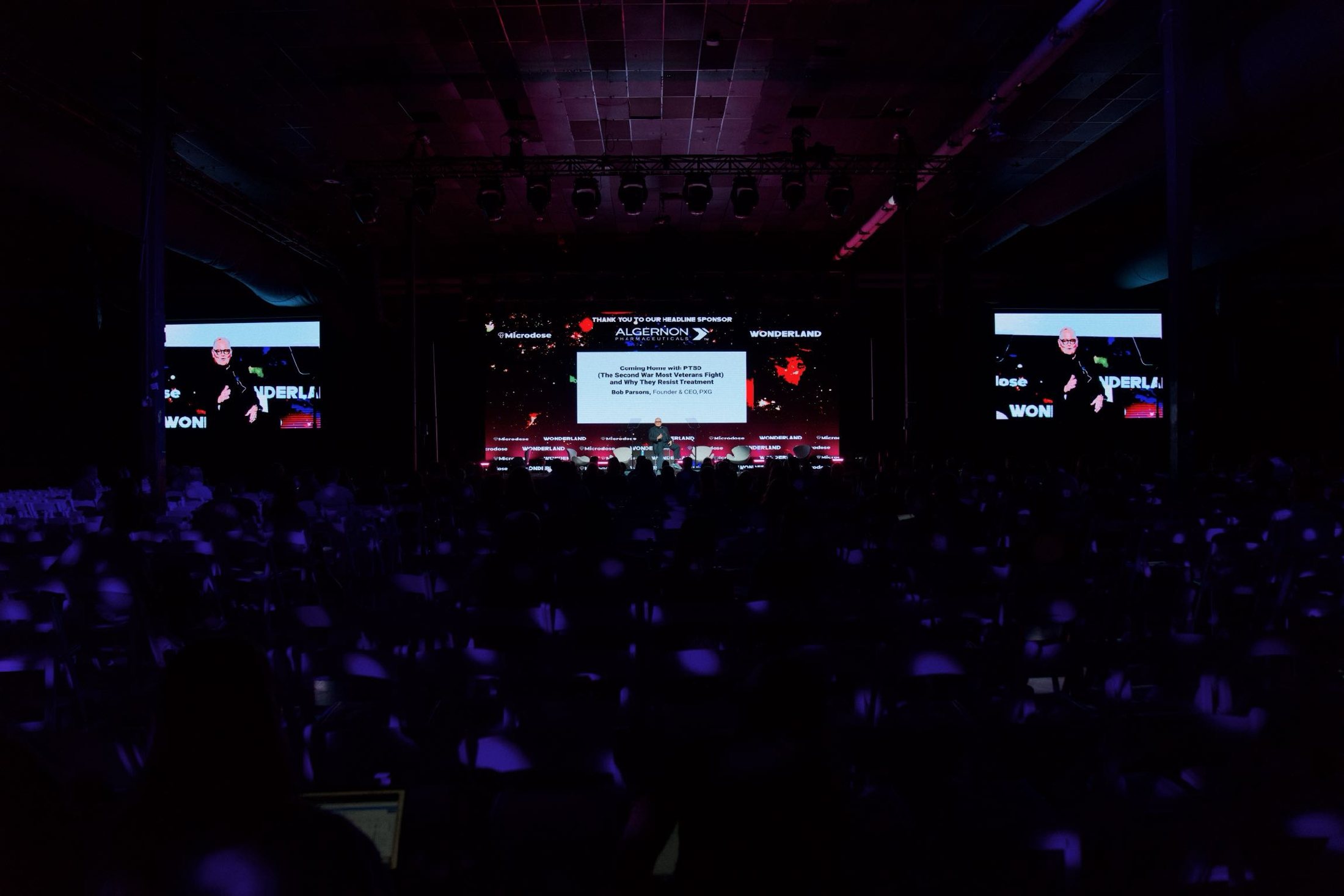 Wide frame of a lit stage seen over a dark crowd.