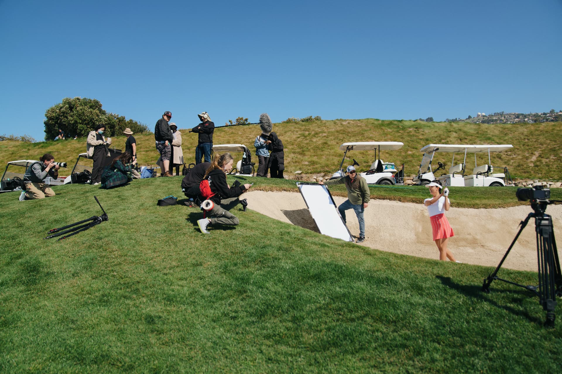 Camera and photography team covering a golf bunker shot.