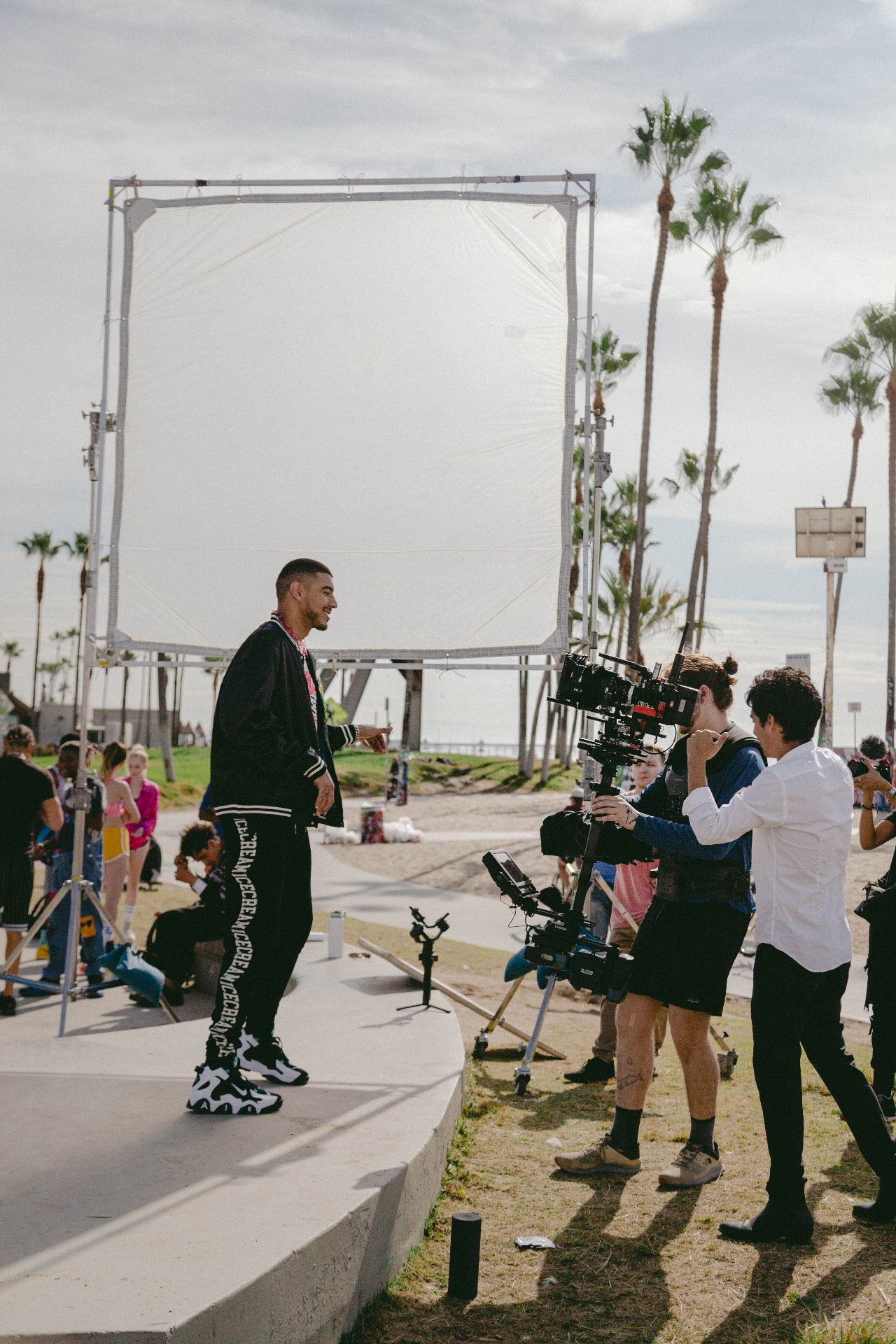 Talent on a Venice Beach set beside a large diffusion frame during a Juanma shoot.