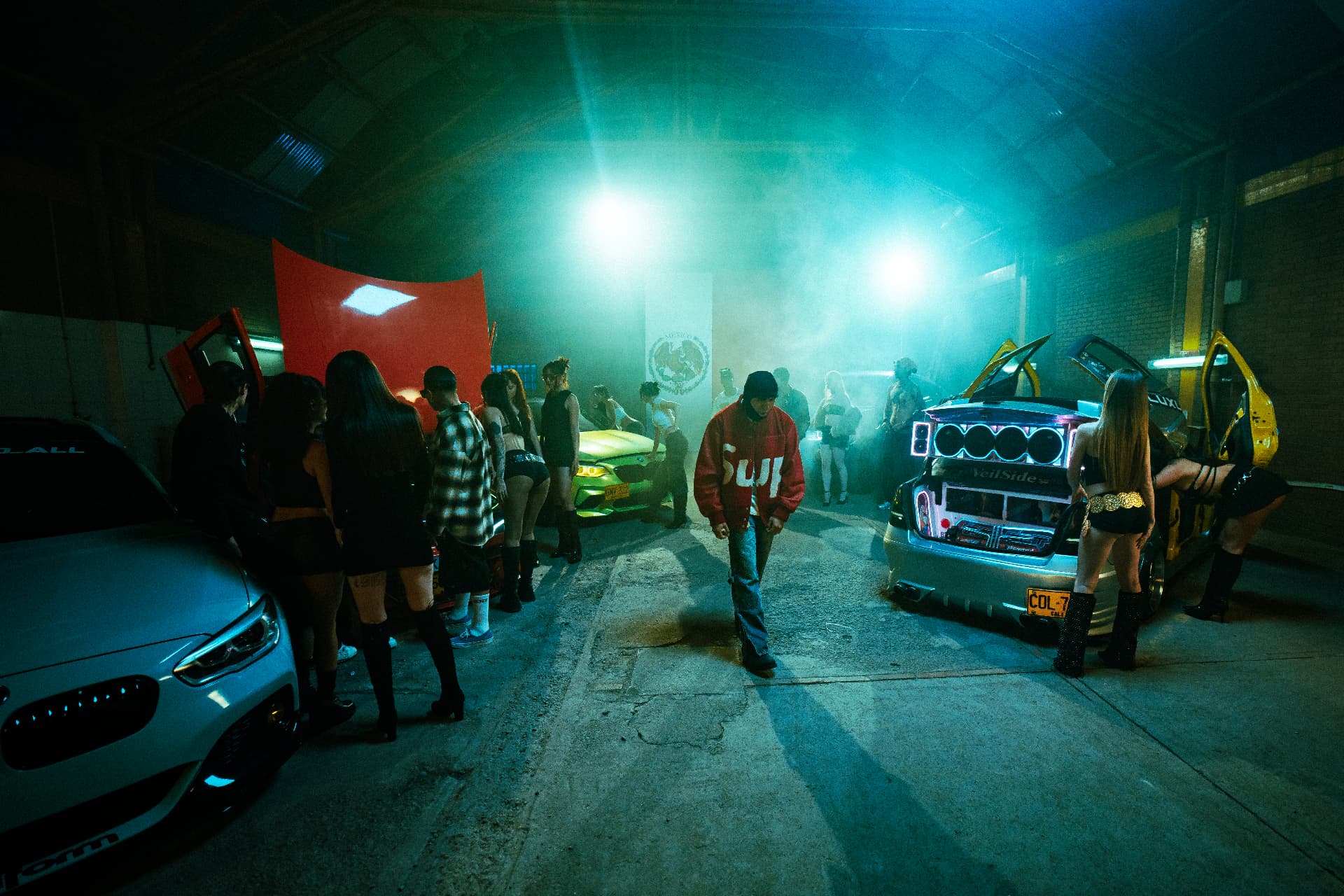 Wide view of the Reloxito set — tuned cars, haze and stage lighting.